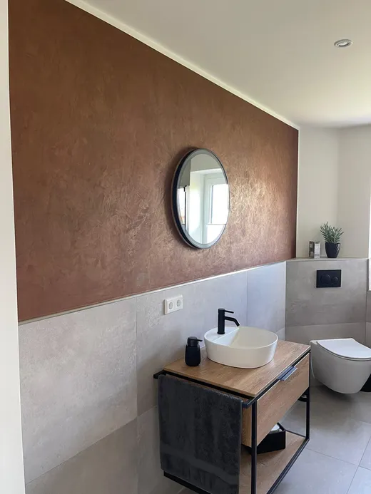 Gäste-WC mit Kupfer-Metallic-Wand und rundem Spiegel
