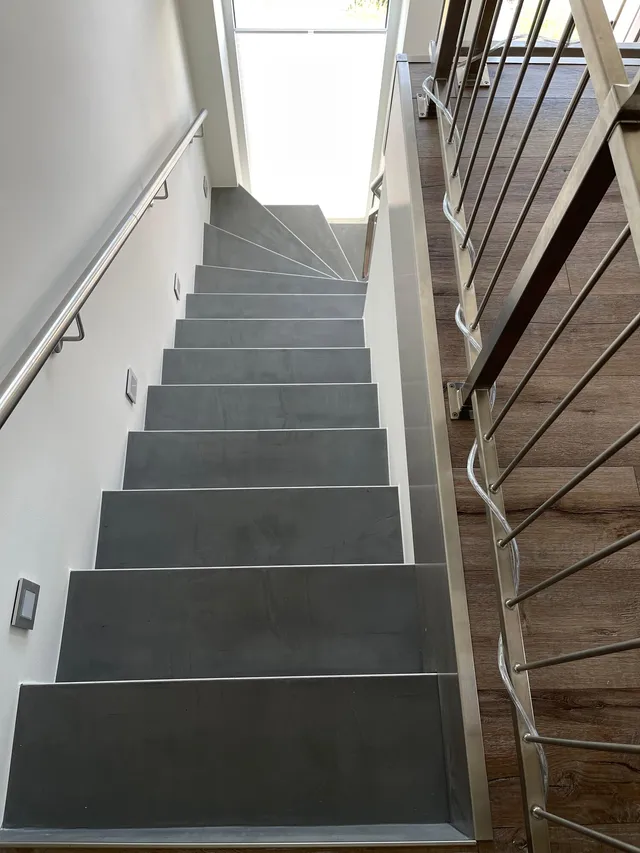 Treppe in fugenloser Betonoptik mit Edelstahlgeländer und Holzboden – Treppenbeschichtung MB Petersen Malerbetrieb Husum